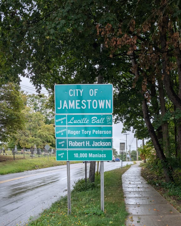 A road sign at the edge of Jamestown listing famous residents: Birthplace of Lucille Ball, Birthplace of Roger Tory Peterson, Home of Robert H. Jackson, Home of 10,000 Maniacs. North Main Street, Jamestown, New York.