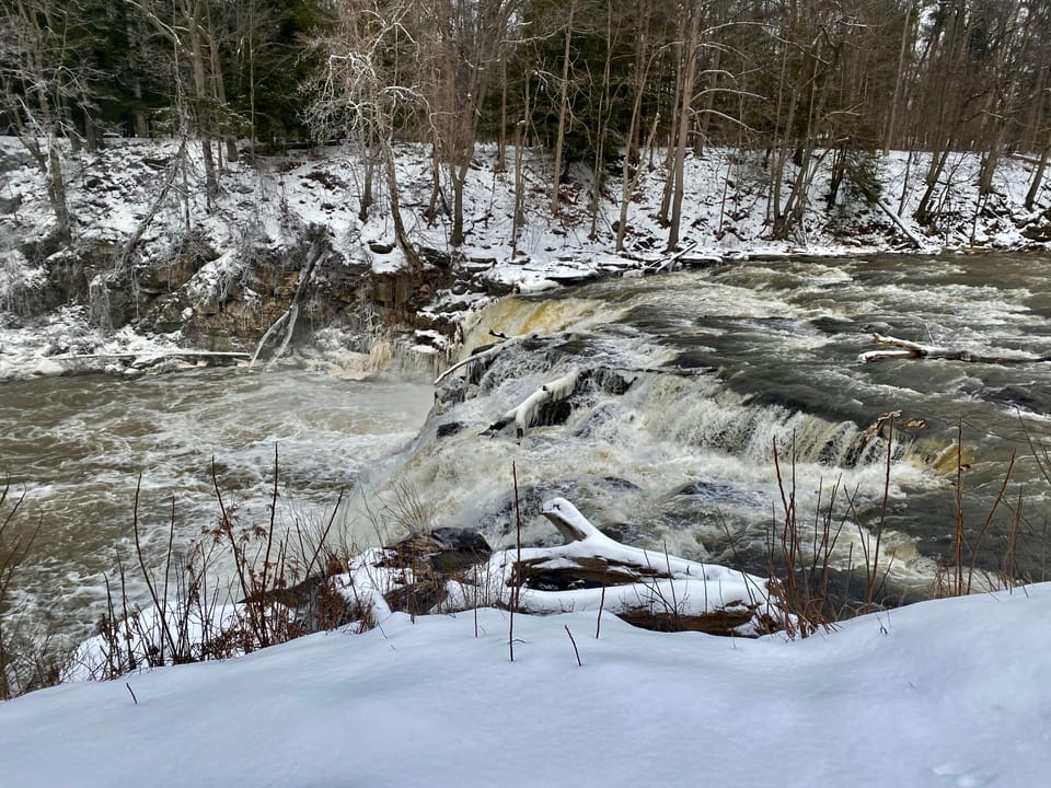 A view of Indian Falls, as seen in January 2023 from the parking lot of the Indian Falls Log Cabin Restaurant in the town of Pembroke, New York (the only publicly accessible view of the falls from land). Locally renowned as a fishing spot, this 20-foot curtain cascade is located at the point where T