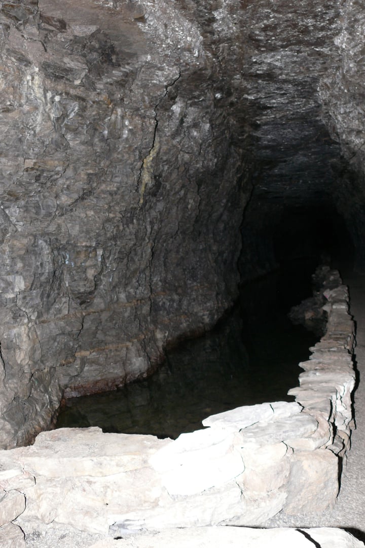 Interior of Lockport Cave showing the water tunnel blasted from solid dolomite rock, with stone walls and low ceiling