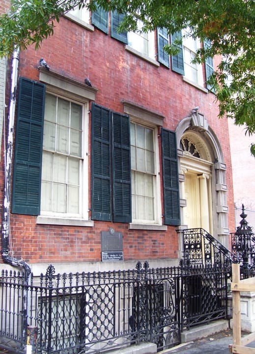 Front facade of the Merchant's House Museum at 29 East 4th Street, NoHo, Manhattan: red-brick Federal-style house with black shutters, marble entrance surround and cast-iron stoop railing, present-day daylight exterior.