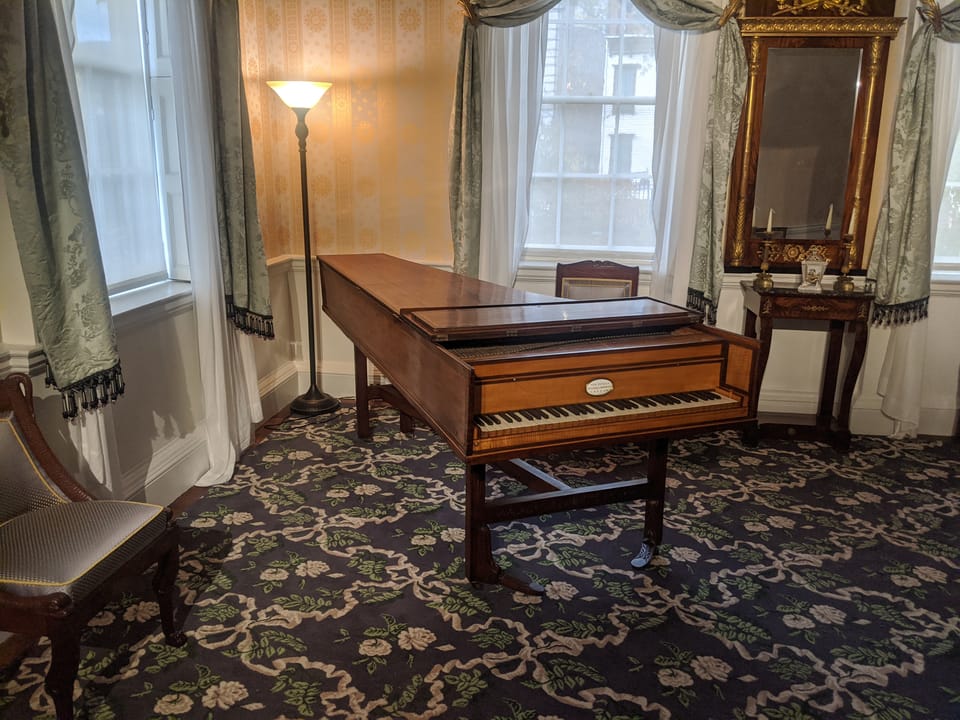 The drawing room at Morris-Jumel Mansion, furnished with a period piano, a museum interior open to visitors