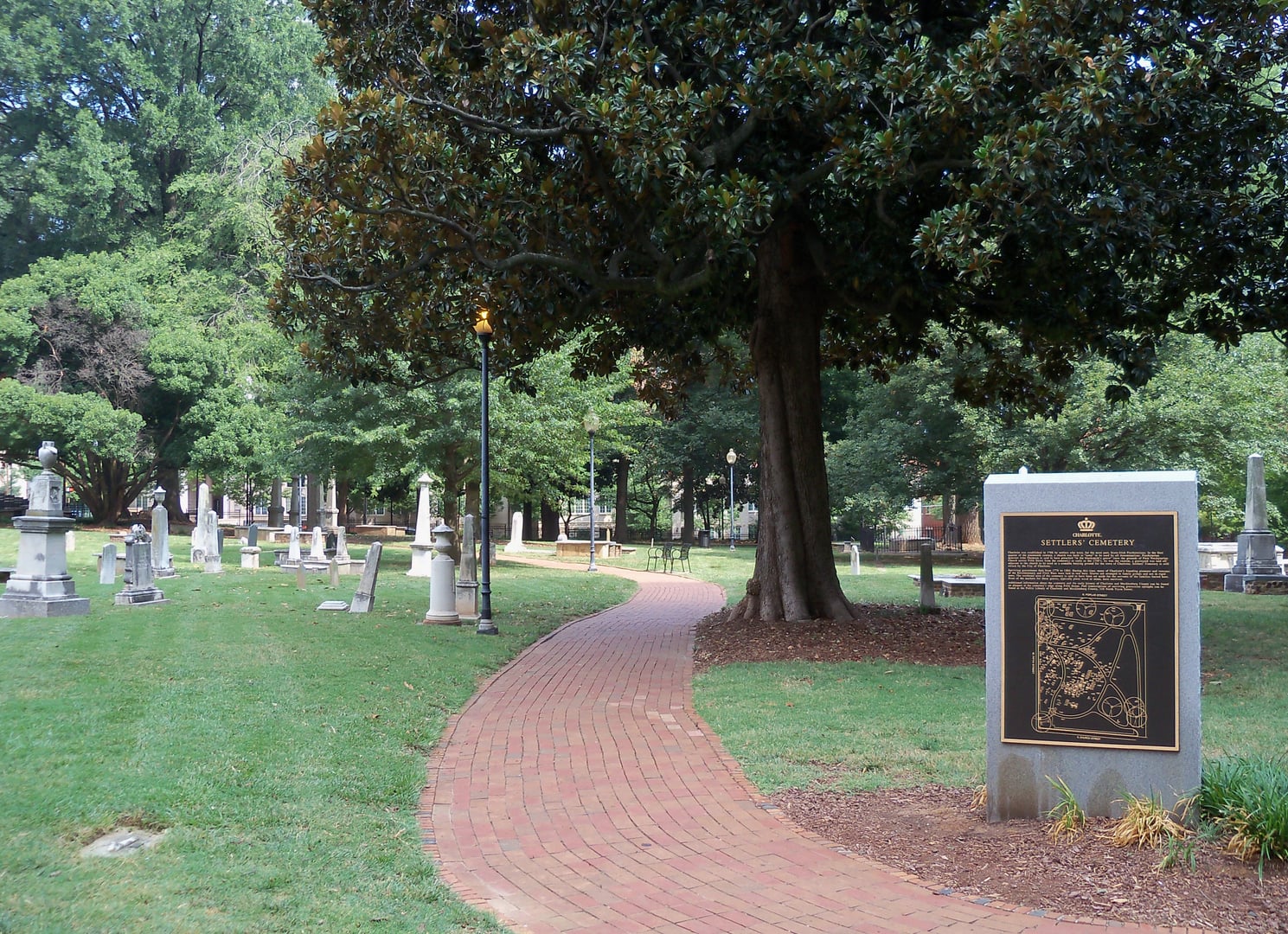 Historic gravestones at Old Settlers' Cemetery in Uptown Charlotte, North Carolina, with First Presbyterian Church visible in the background.