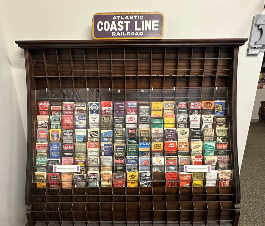 A wall case of Atlantic Coast Line Railroad matchbooks and paper ephemera on display inside the museum.