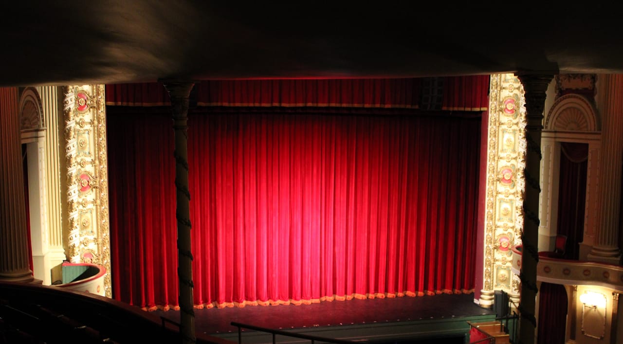 The gilded proscenium arch and red stage curtain inside Thalian Hall, March 2023.