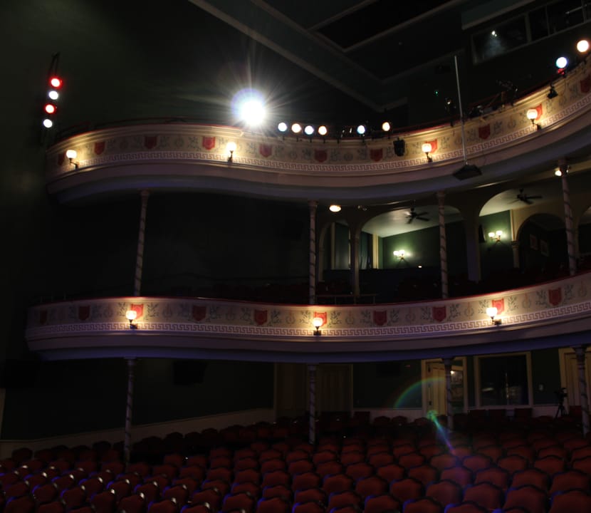 The two curved balcony tiers and painted shield-and-garland frieze, seen from the orchestra level of Thalian Hall, March 2023.