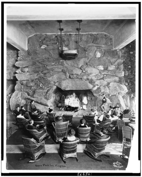 Hotel guests seated in wicker chairs before the massive stone fireplace in the Grove Park Inn's Great Hall lounge, c1913, shortly after the hotel opened.