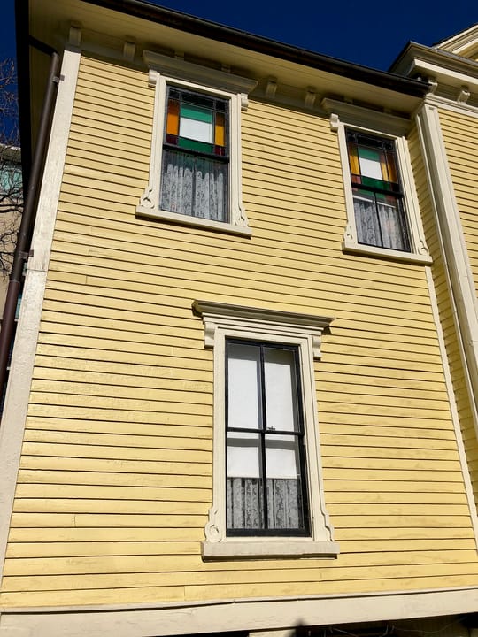 Detail of the Thomas Wolfe Memorial's yellow clapboard siding and stained-glass windows