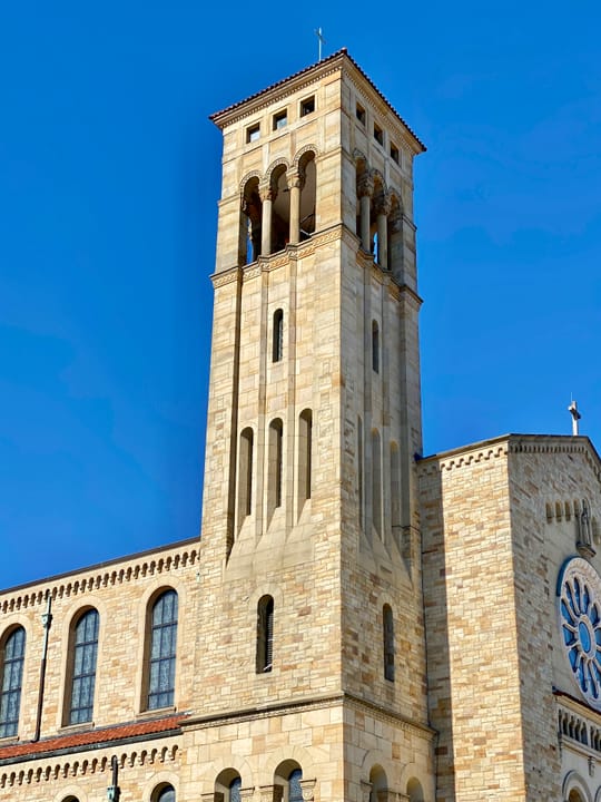 Built between 1929 and 1931, this Romanesque Revival-style church was designed by Joseph Steinkamp to house the congregation of St. William Catholic Church, founded in 1909.  Towering over the corner of West 8th Street and Sunset Avenue, the sandstone-clad church features a red tile roof, roman arch