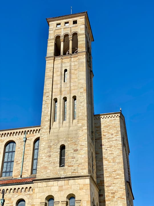 Built between 1929 and 1931, this Romanesque Revival-style church was designed by Joseph Steinkamp to house the congregation of St. William Catholic Church, founded in 1909.  Towering over the corner of West 8th Street and Sunset Avenue, the sandstone-clad church features a red tile roof, roman arch