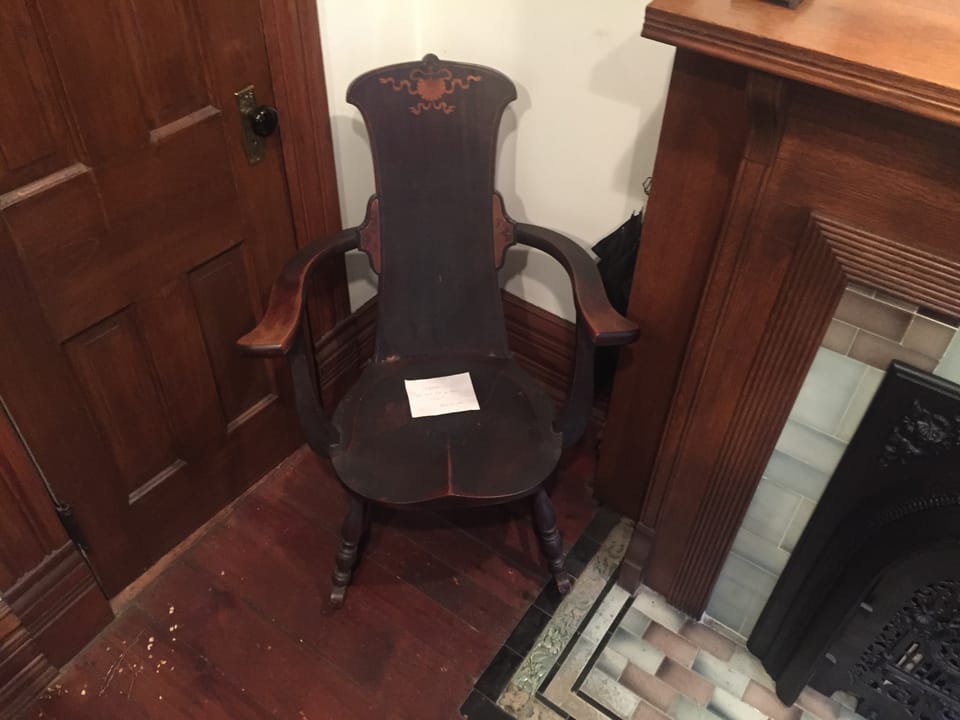 An antique inlaid armchair beside a tiled fireplace inside the Thurber House.
