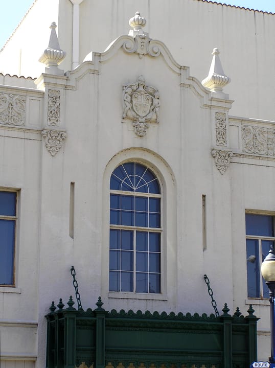 Close detail of the Coleman Theatre's Spanish Colonial Revival facade: the carved pediment, finials and arched window above the marquee, Miami, Oklahoma.