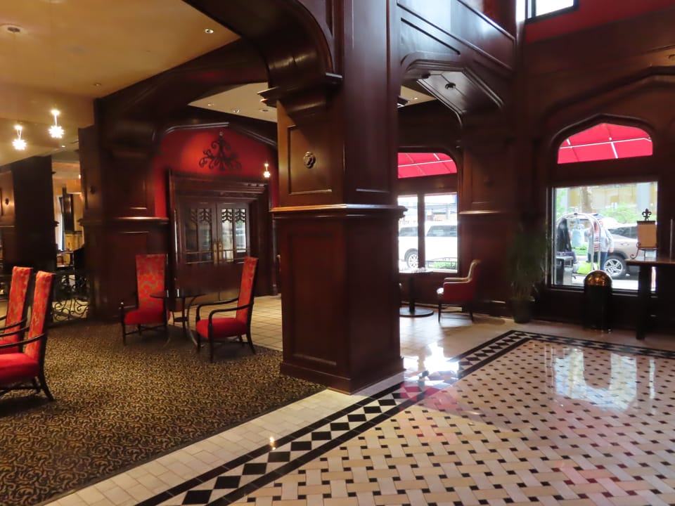 The dark-wood-paneled lobby of the Skirvin Hilton, with its carved columns and patterned marble floor, 2022.