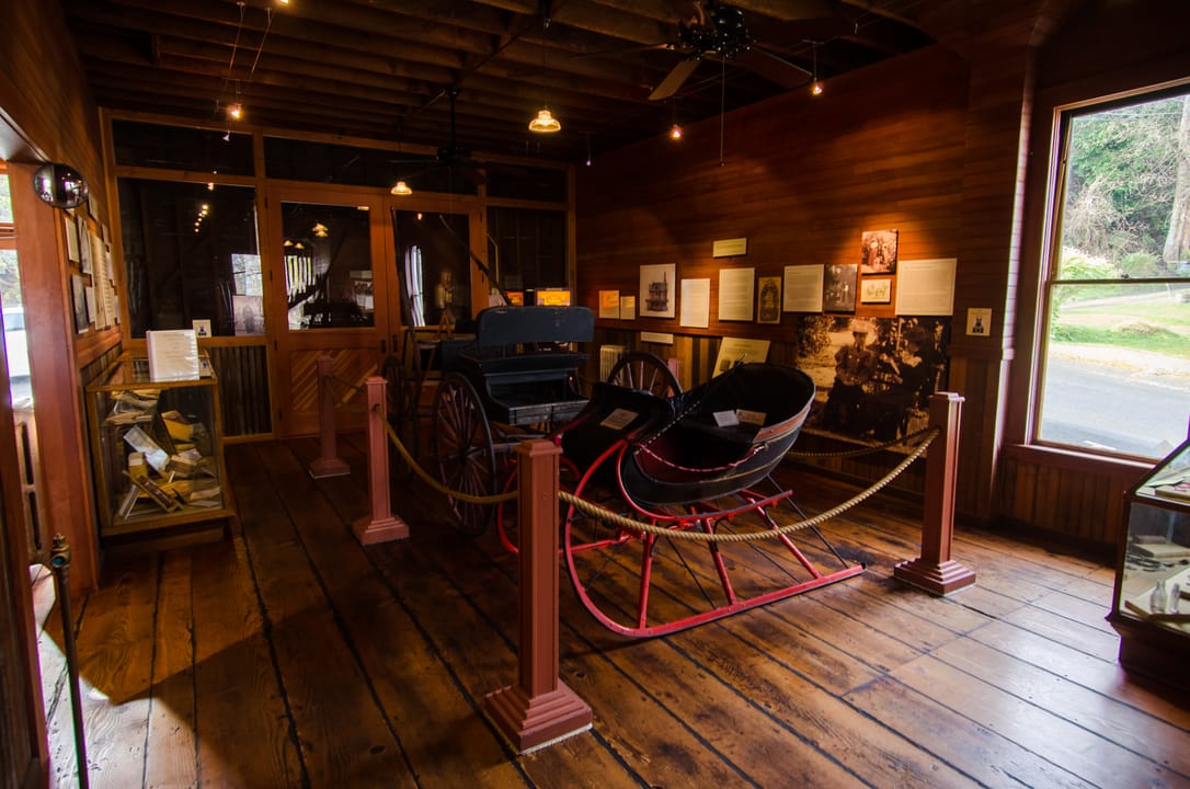 The carriage house museum interior, with a horse-drawn carriage and sleigh on display