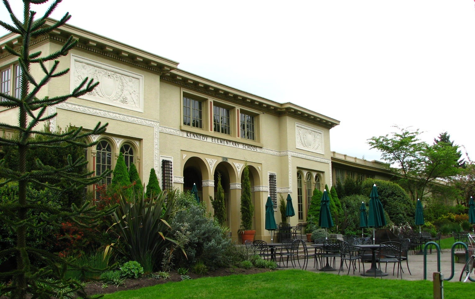 Multi-arched Mission Revival brick entry facade of the 1915 Kennedy School building at 5736 NE 33rd Avenue in Portland, Oregon, now operating as McMenamins Kennedy School hotel and brewpub