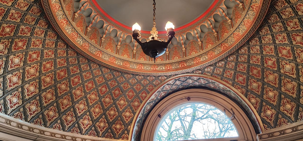 The hand-painted oval dome ceiling above the Pittock Mansion's staircase, with its bronze chandelier and leaded-glass oculus window, Portland, Oregon.