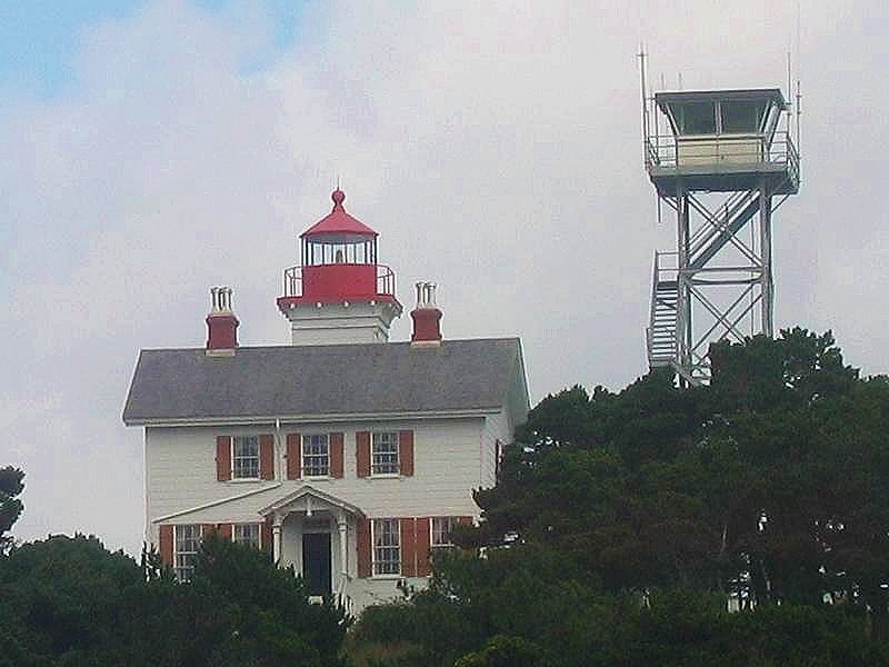 White wooden Yaquina Bay Lighthouse with attached keeper's quarters in Newport Oregon
