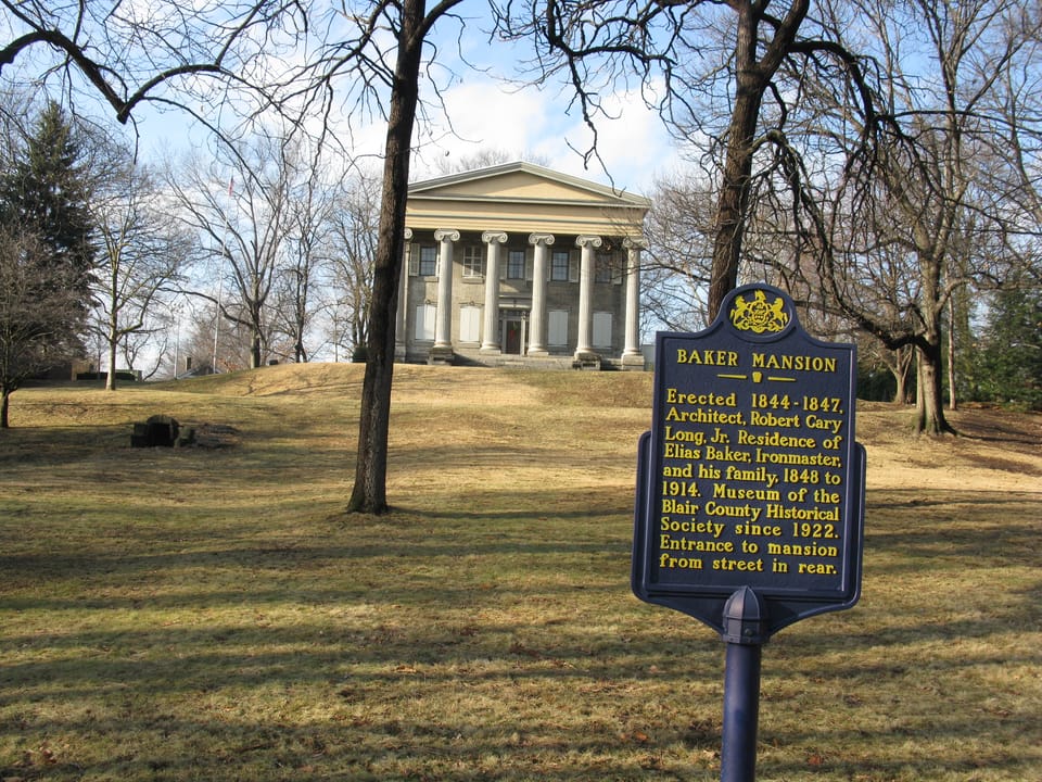 Angled view of Baker Mansion with the Pennsylvania state historical marker in the foreground, reading "Baker Mansion, Erected 1844-1847, Architect Robert Cary Long Jr., Residence of Elias Baker, ironmaster, and his family 1846 to 1914. Museum of the 