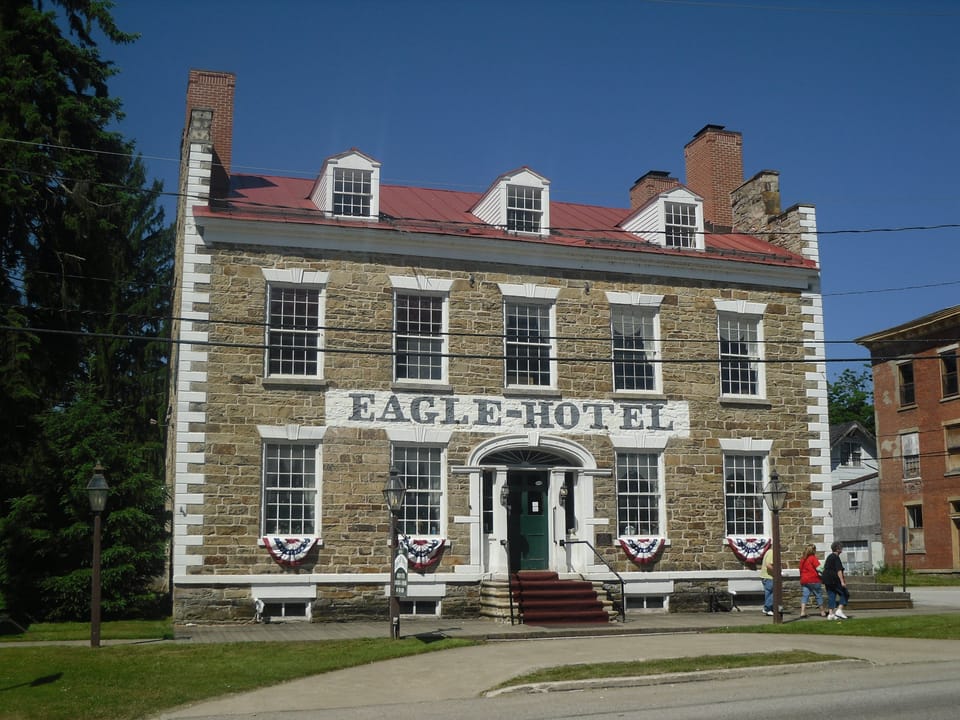 1933 Historic American Buildings Survey photograph of the 1826 fieldstone Eagle Hotel in Waterford, Pennsylvania, showing the east elevation and front facade of the two-and-a-half-story L-shaped stagecoach inn.