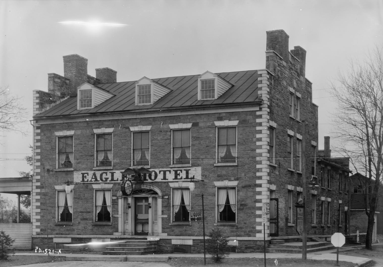 1933 Historic American Buildings Survey photograph of the 1826 fieldstone Eagle Hotel in Waterford, Pennsylvania, showing the east elevation and front facade of the two-and-a-half-story L-shaped stagecoach inn.
