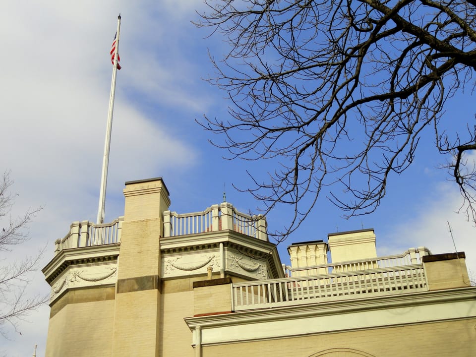 Rooftop balustrade, paired chimneys and flagpole atop Clayton, seen from below against a blue sky, March 2012.
