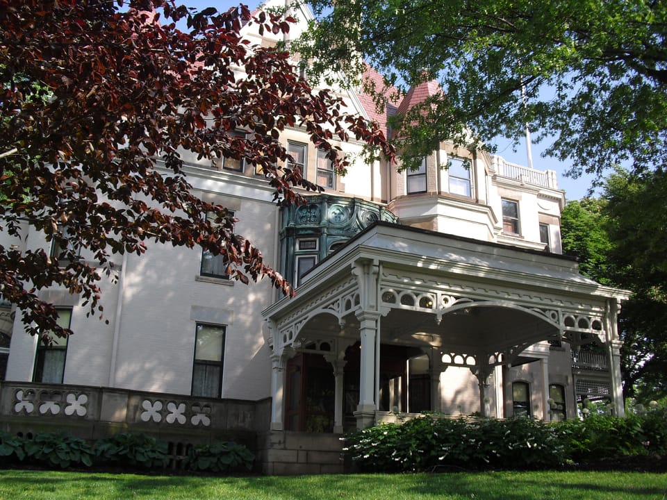 Clayton's front porte-cochere and bay windows seen through autumn foliage, uploaded 2010.