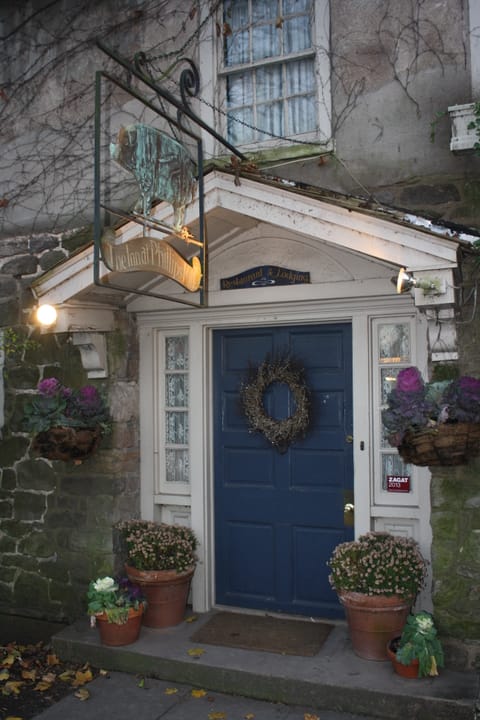 The Inn at Phillips Mill's front entrance, with its hanging pig sign, "Restaurant & Lodging" plaque and blue door, New Hope, Pennsylvania (2012).