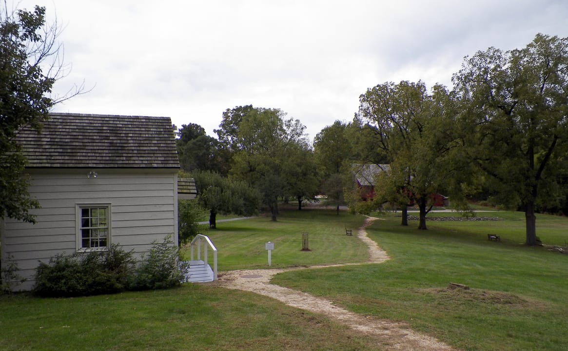 A grounds view at Rock Ford Plantation, a small outbuilding and path leading toward the mansion in the distance.