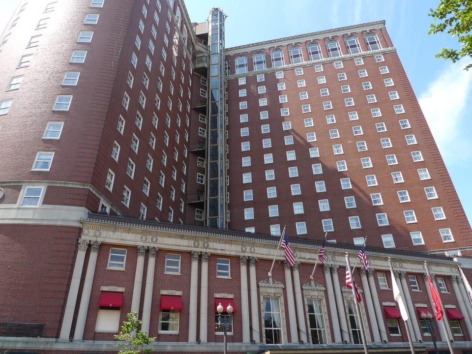 Exterior view of the Biltmore Hotel in downtown Providence, Rhode Island, with its ground-floor awnings and flags along Dorrance Street.