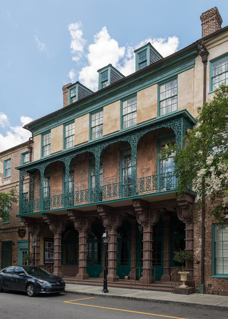 Exterior facade of the Dock Street Theatre on Church Street in Charleston, South Carolina, with its iron balcony and tall arched windows on the historic French Quarter building.