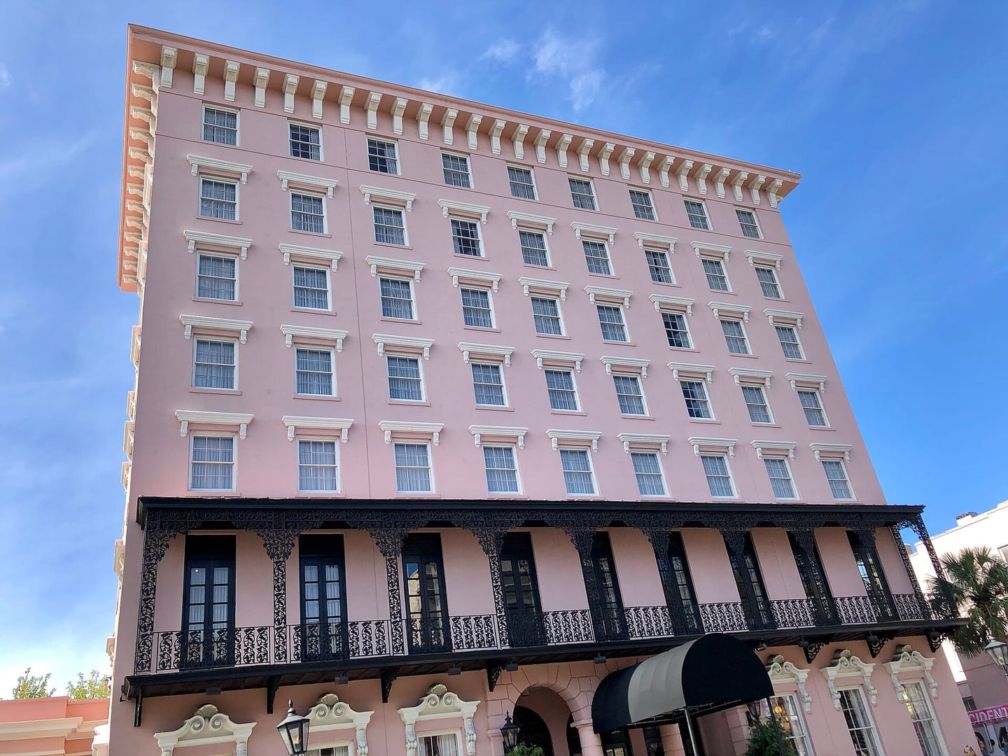Exterior of the Mills House Hotel in Charleston, an Italianate-style building with peach stucco facade and arched windows in the city's French Quarter.