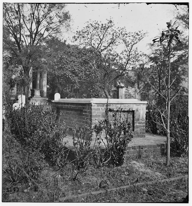 Looking into St. Philip's Episcopal Church graveyard through its iron gate, with box tombs and headstones beneath live oaks, Charleston, South Carolina, 2019.
