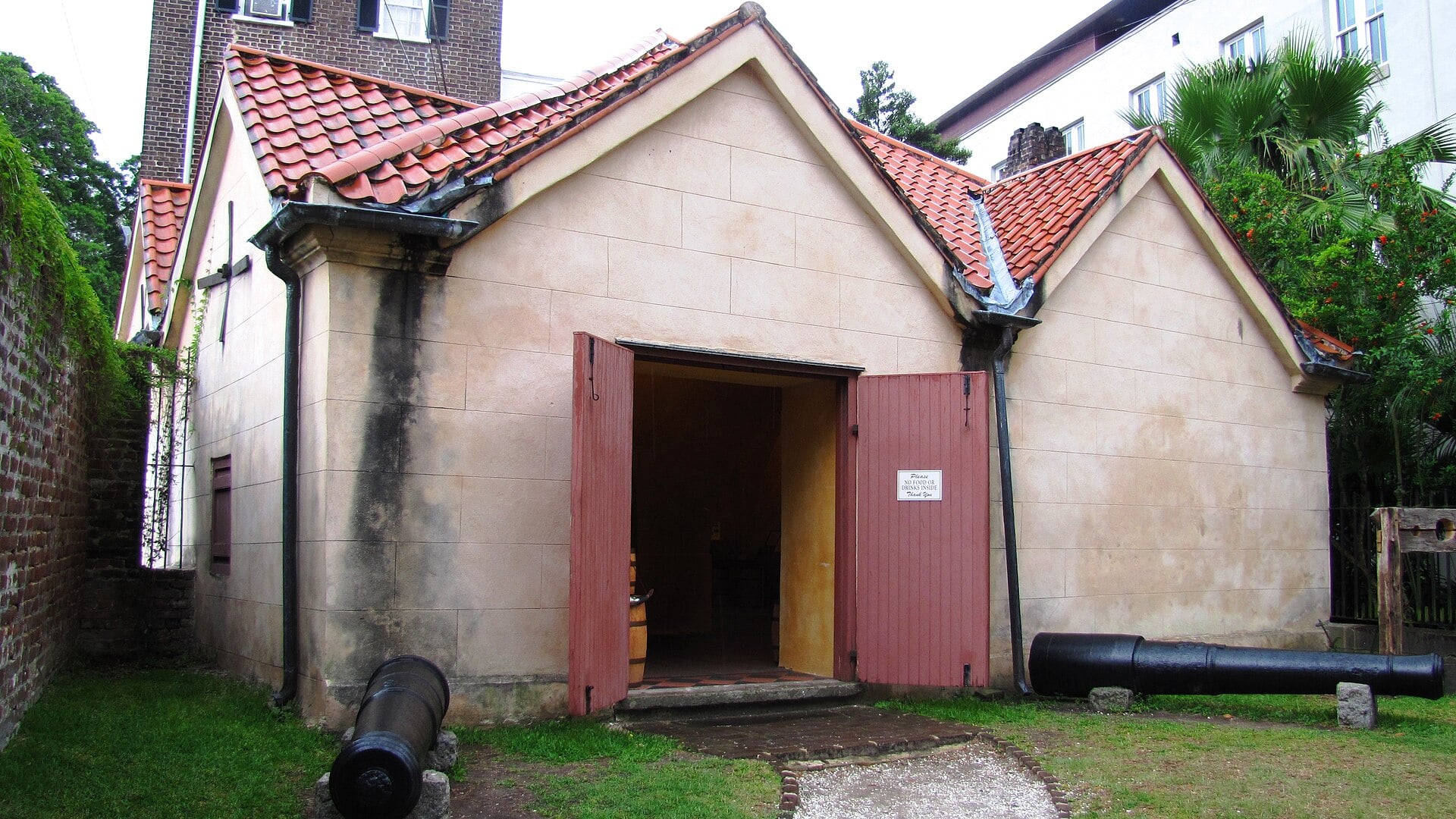 The 1713 Powder Magazine, a small brick fortress-style colonial structure with steep red tile roof on Cumberland Street, Charleston, SC