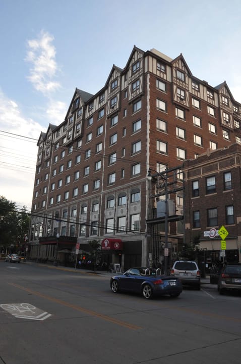 Full view of the hotel's stepped-gable Tudor Revival tower and red canopy sign from across the street; Commons file description reads in part: 'ALEX JOHNSON HOTEL; OPENED IN 1928 ... THIS IS A PREMIER SITE IN THE HISTORIC DISTRICT.'