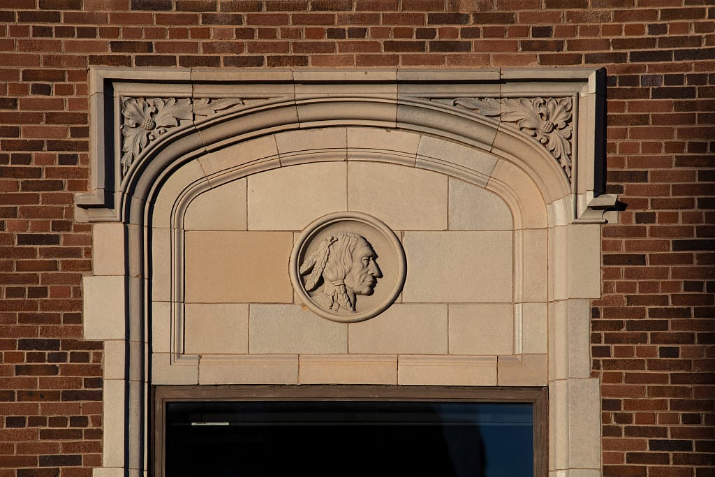 Carved stone roundel of a Native American profile over a side-entrance arch, part of the hotel's original 1928 Tudor/Art Deco ornamentation. Photographed by Carol M. Highsmith, 2021, Library of Congress.