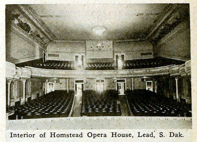 The auditorium of the Homestake Opera House in Lead, South Dakota, looking toward the rear, with its curved, ornamented balcony and rows of seats, as printed in a 1916 periodical, before the 1984 fire.
