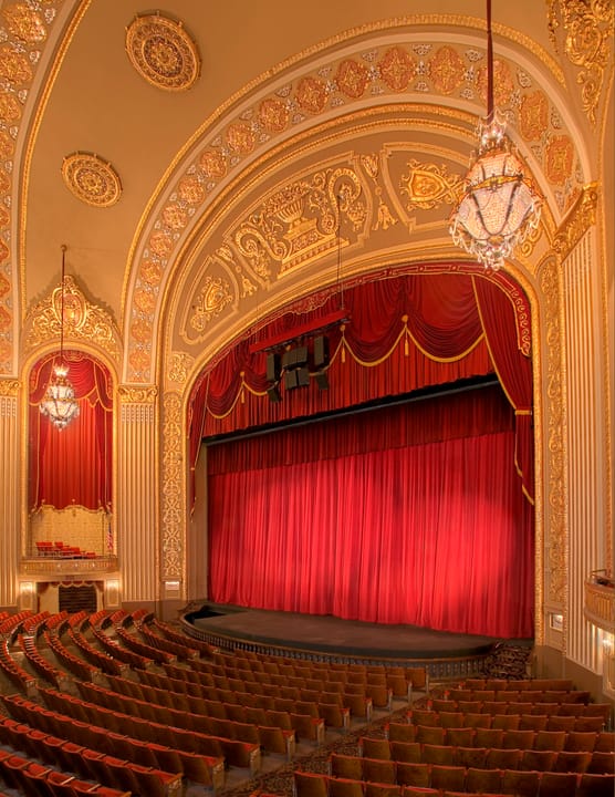 The restored auditorium of the Orpheum Theatre, looking at the proscenium arch, ornate ceiling and red stage curtain.