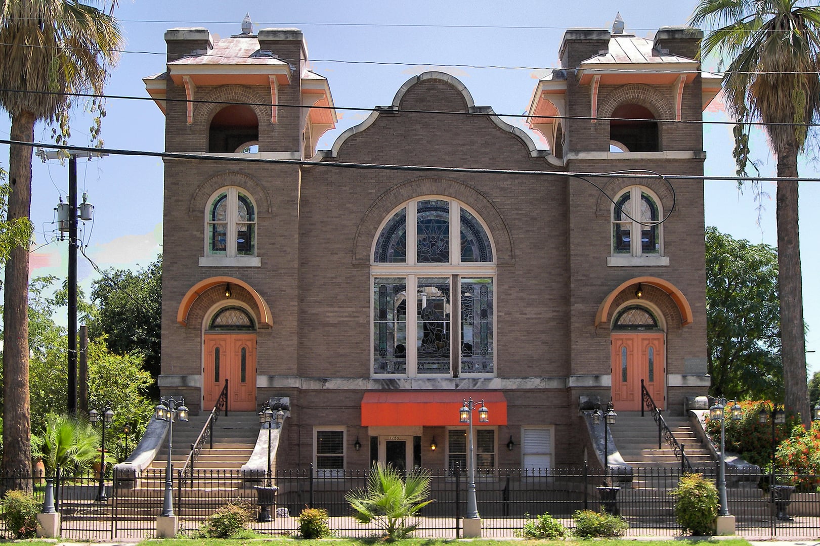 Exterior of the 1912 former Alamo Methodist Church at 1150 S Alamo Street in San Antonio, Texas — Mission Revival style with arched entryway and courtyard
