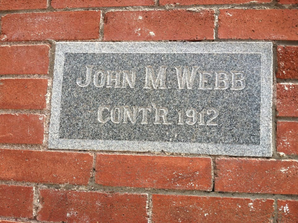 The contractor's stone on the west end of the north-facing wall of the Hancock Building has text stating "John M. Webb contr. 1912"
