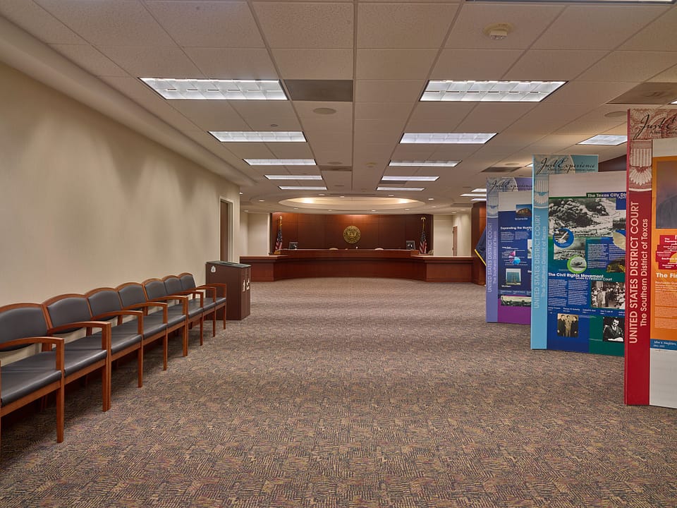 A public reception lobby inside the Bob Casey Federal Courthouse, with seating and historical exhibit panels on the Southern District of Texas, Houston.