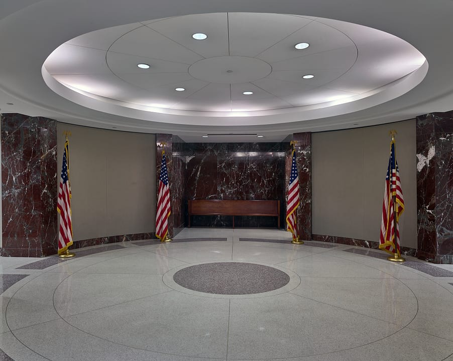 The circular entrance rotunda of the Bob Casey Federal Courthouse, with marble walls, American flags and a domed ceiling, Houston, Texas.