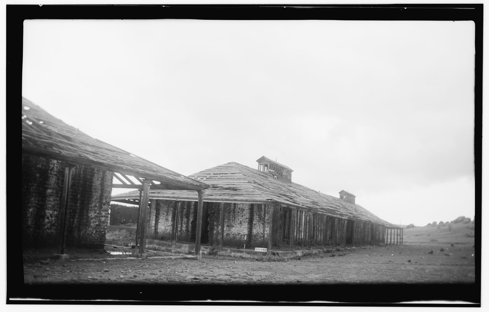 1936 Historic American Buildings Survey photograph of officers' quarters at Fort Davis, Texas, showing the southeast elevation with adobe walls and wood-frame porch under the Davis Mountains.
