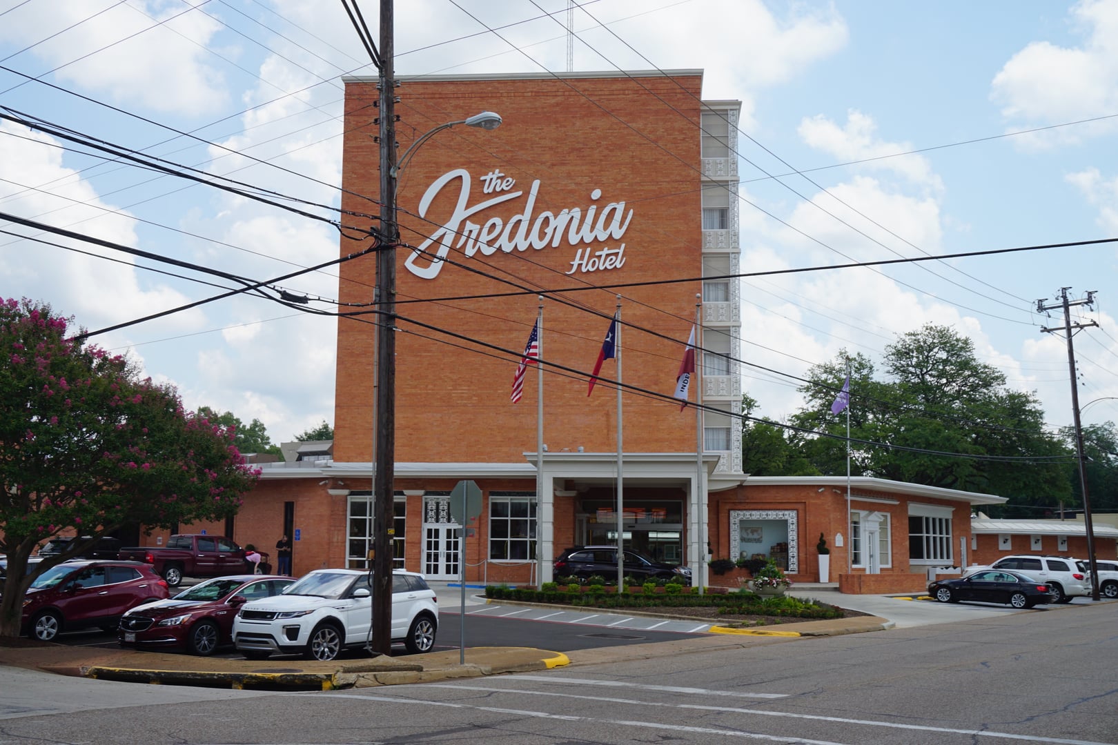 Six-story mid-century International Style tower of the Fredonia Hotel rising above downtown Nacogdoches, Texas, with its one-story curved cabana wing visible at street level