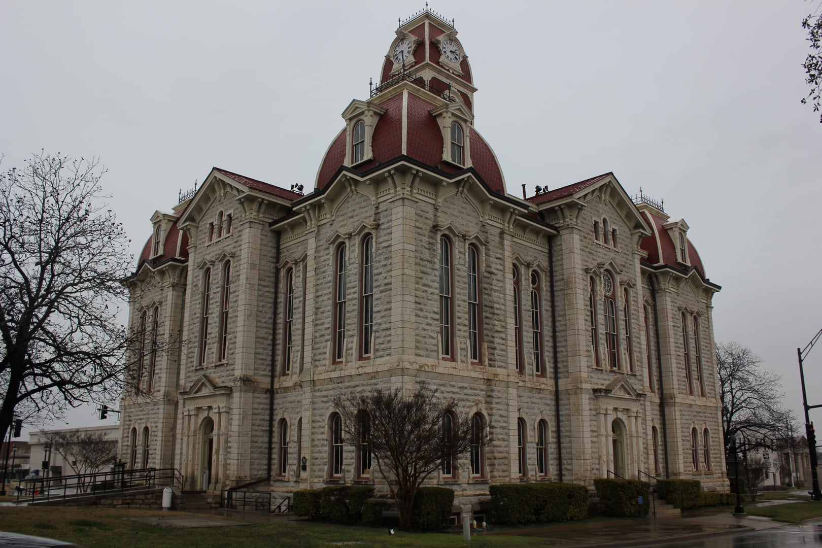 Parker County Courthouse in Weatherford, Texas—a three-story Second Empire limestone building with a central tower and mansard roofline, photographed from the courthouse square