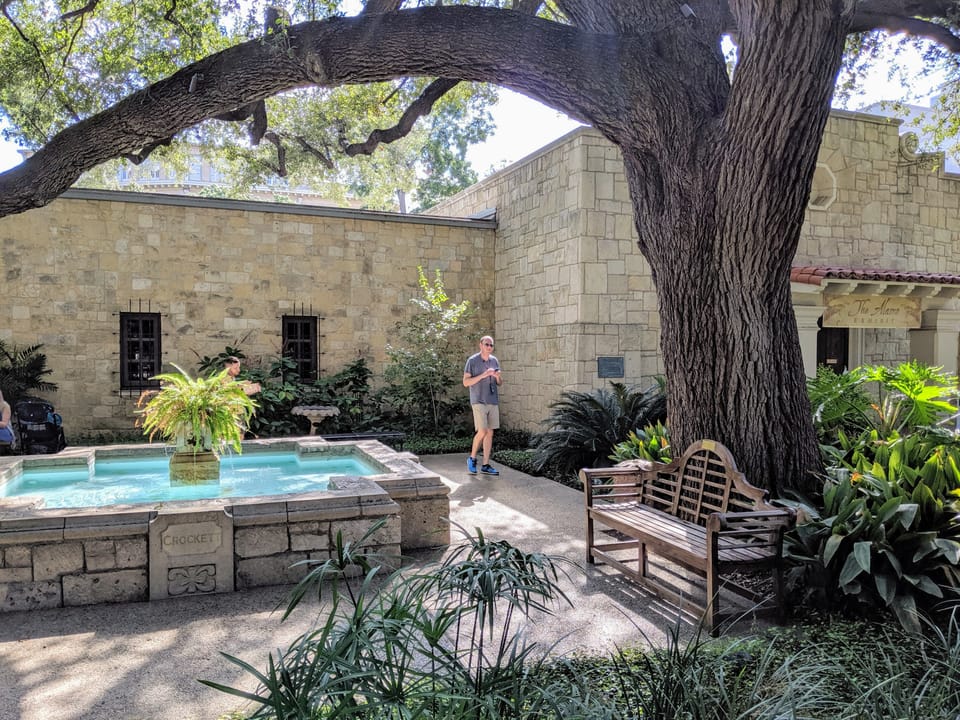 The fountain and courtyard garden behind the Alamo church, under its landmark live oak tree, San Antonio, Texas