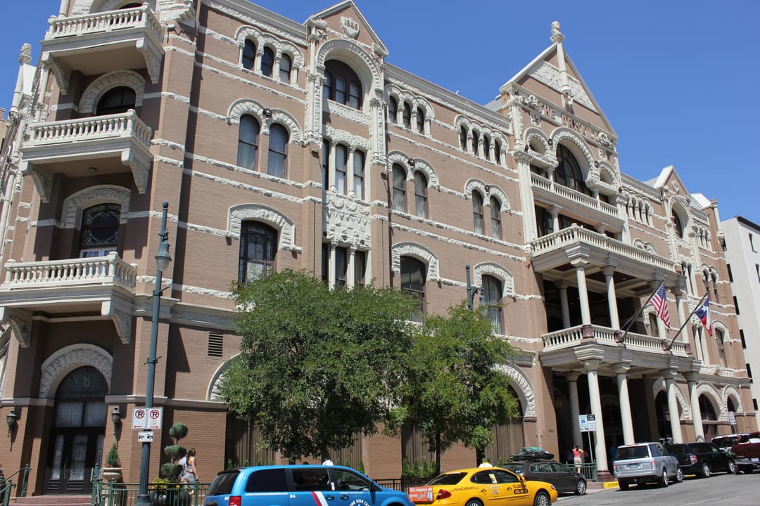 Daytime street view of the Driskill with Texas and American flags flying from its balconies.