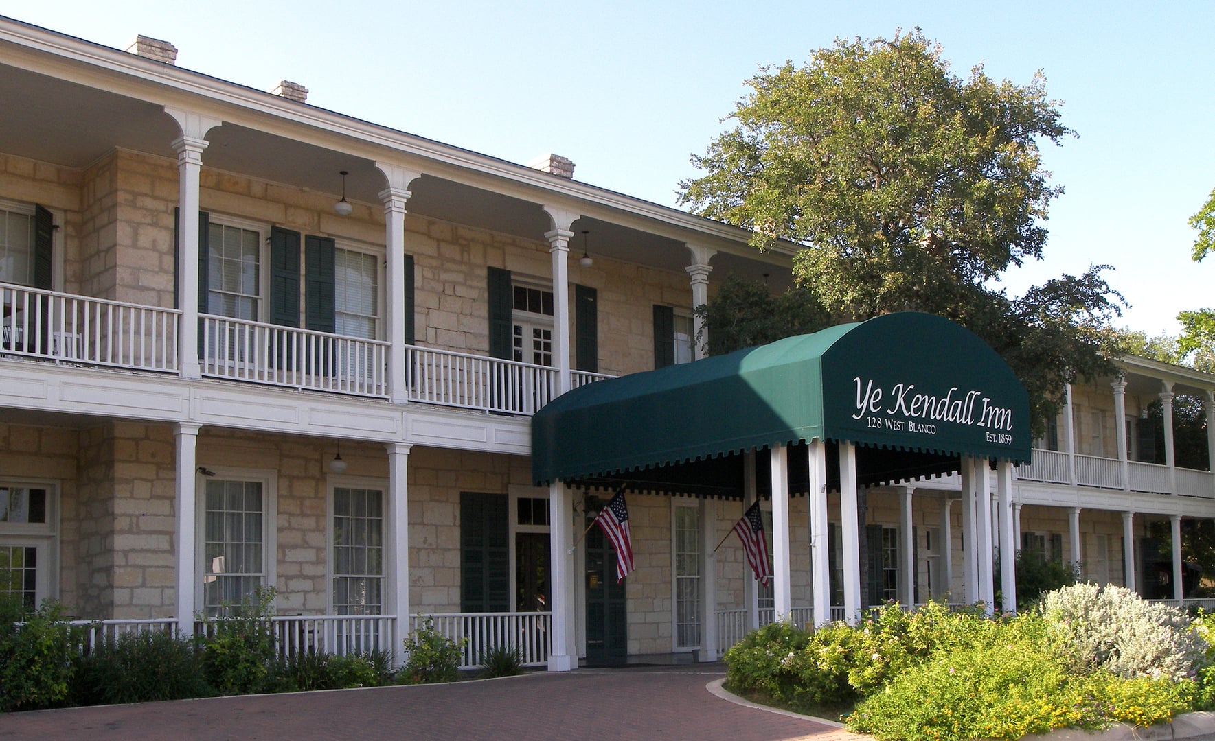 Limestone facade of the 1859 Kendall Inn in Boerne, Texas, a two-story Greek Revival structure with a covered porch