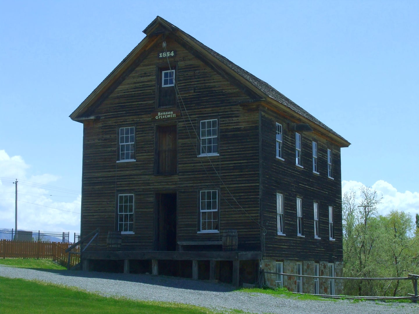 Benson Grist Mill in Stansbury Park, Utah — a restored 1854 pioneer grist mill with wood siding and weathered exterior, surrounded by open land