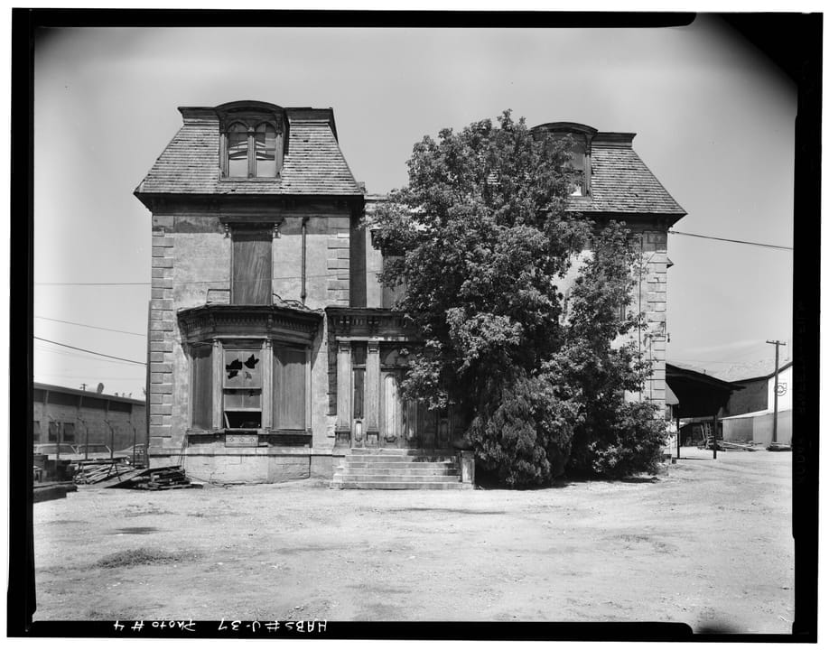 The south (front) elevation of the Devereaux Mansion in 1967, boarded and overgrown before its later restoration -- same mansard roof, dormers and tower as the current hero's restored exterior.