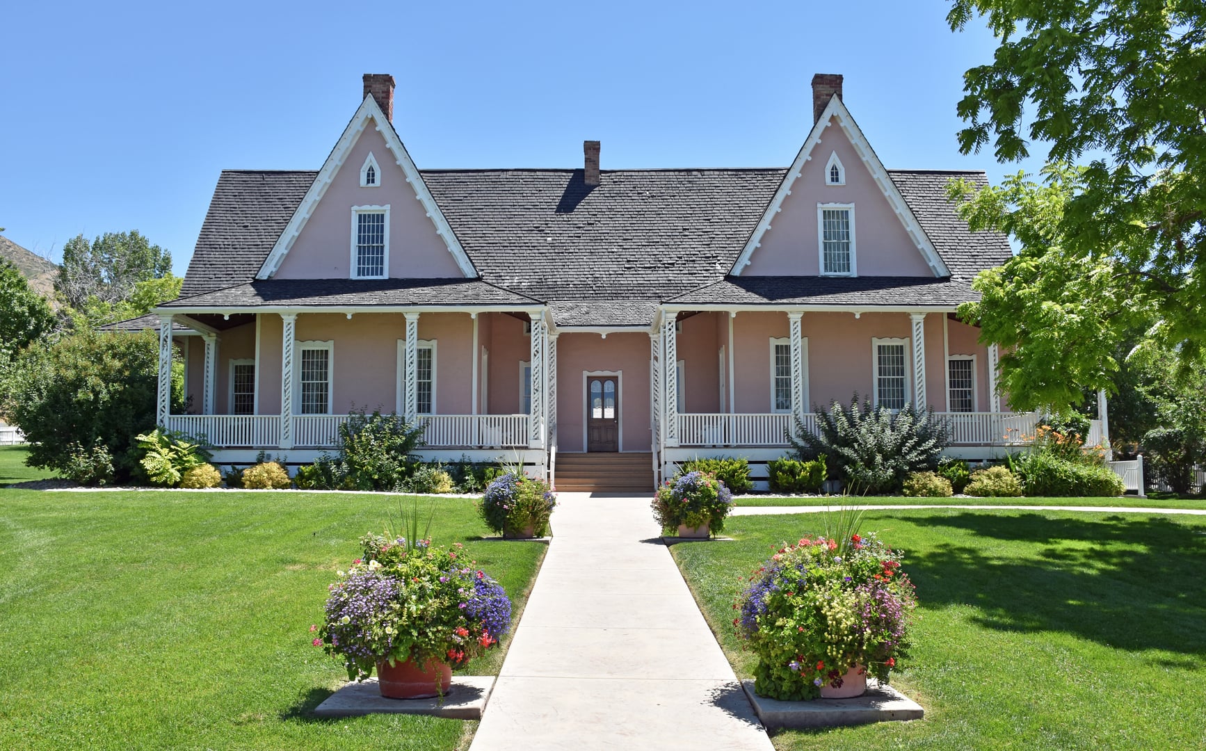The Brigham Young Forest Farmhouse at This Is the Place Heritage Park, Salt Lake City — a Gothic Revival cottage with white stucco walls and decorative trim, photographed July 2019