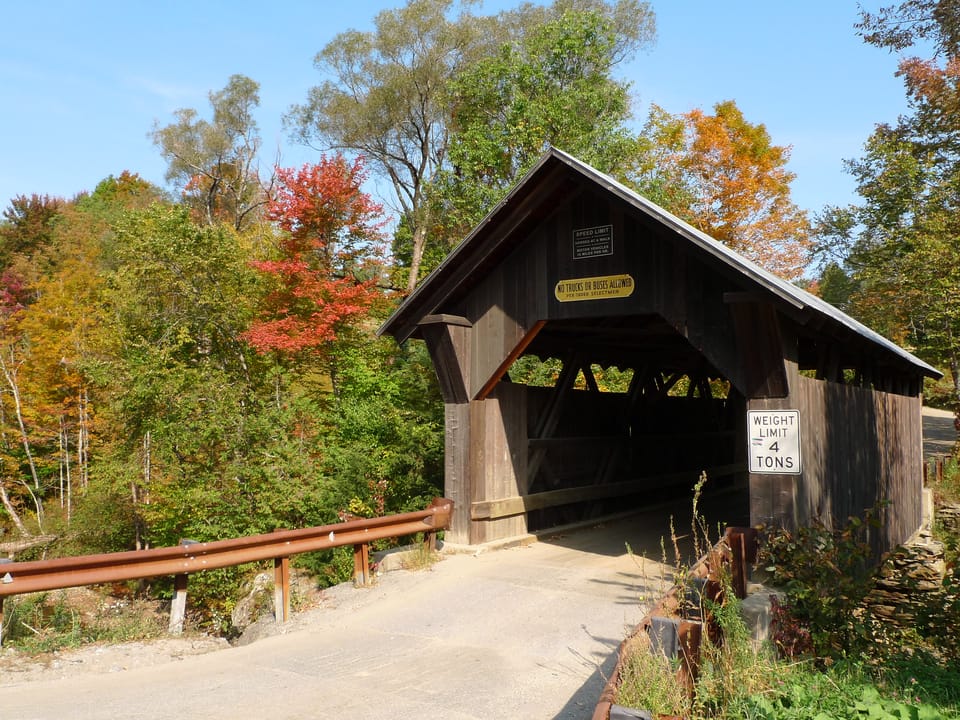 The Gold Brook Covered Bridge (Emily's Bridge) in Stowe, Vermont, seen from the approach road in autumn foliage, with the portal signs and a 4-ton weight-limit sign, September 2008.